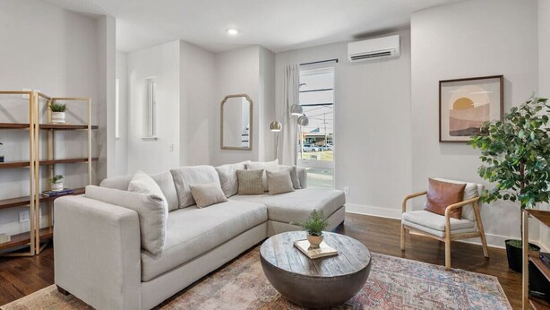 A modern living room with a sectional sofa, a round coffee table, a side chair, and a bookshelf.