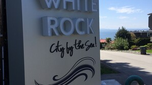 Willkommensschild für White Rock, Stadt am Meer, mit einer Steinsäule und freiem Blick auf den Ozean im Hintergrund.