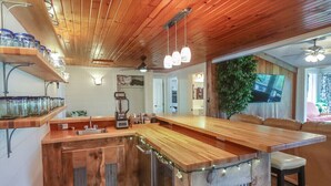 A kitchen with wooden cabinets, a built-in island, and a seating area with a large plant. - Beautiful golf course getaway on Madeline island<br> (La Pointe)