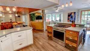 A kitchen with a central island, wooden cabinets, and a large stove. - Beautiful golf course getaway on Madeline island<br> (La Pointe)