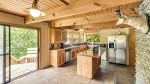 Une cuisine spacieuse avec des meubles en bois, un îlot central et un sol en pierre.