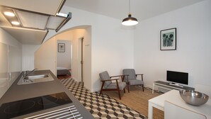 Een moderne keuken met een inbouwfornuis, een spoelbak en een eethoek met een televisie en zitplaatsen.