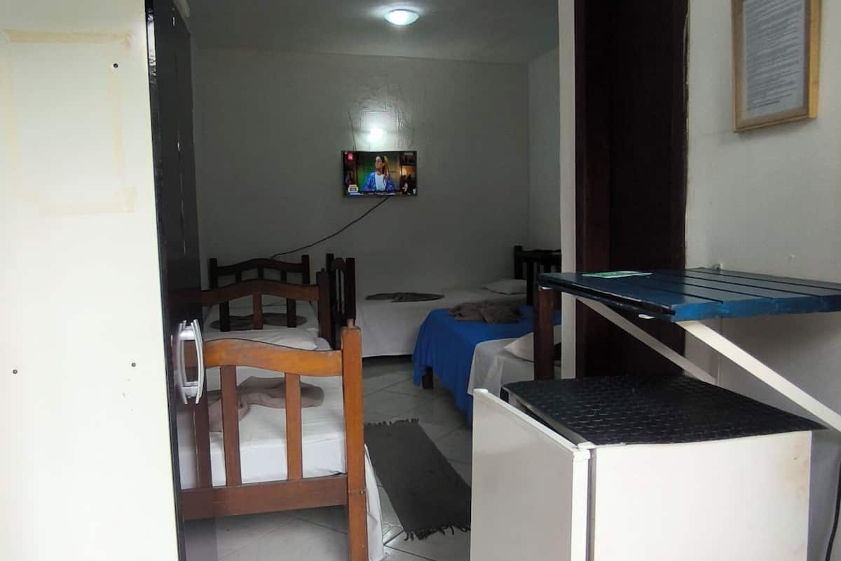 Um quarto com uma cama, uma escrivaninha, uma cadeira e uma televisão.