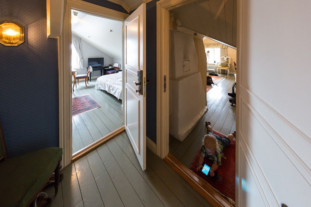 Une chambre d’hôtel avec un grand lit, un bureau et une chaise. Une porte coulissante donne accès à une autre pièce.