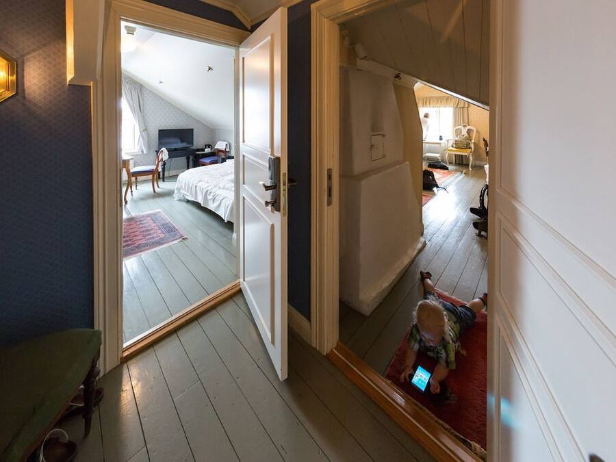 Une chambre d’hôtel avec un grand lit, un bureau et une chaise. Une porte coulissante donne accès à une autre pièce.