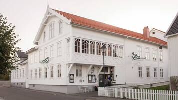 Traditional architecture meets modern charm at this inviting hotel, featuring a symmetrical facade with ornate detailing and a cozy outdoor seating area.