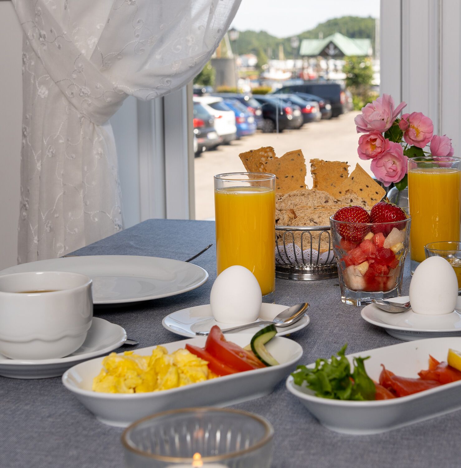 A breakfast table with plates of eggs, toast, fruit, and juice.