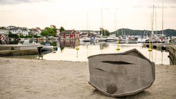 Enjoy a serene harbor view with boats docked along the water's edge, featuring a large stone structure and a picturesque backdrop of calm waters and surrounding buildings.
