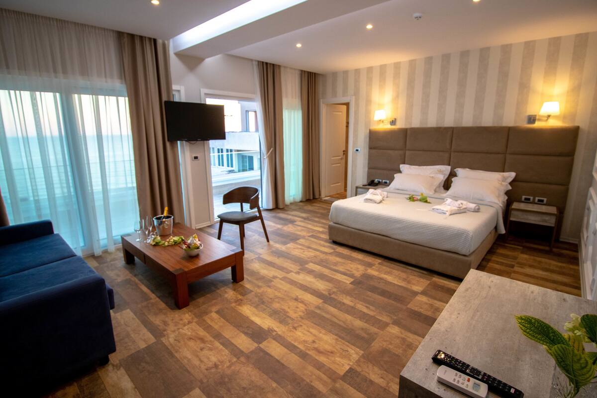 A hotel room with a bed, a desk, a chair, a TV, and a balcony with a view.