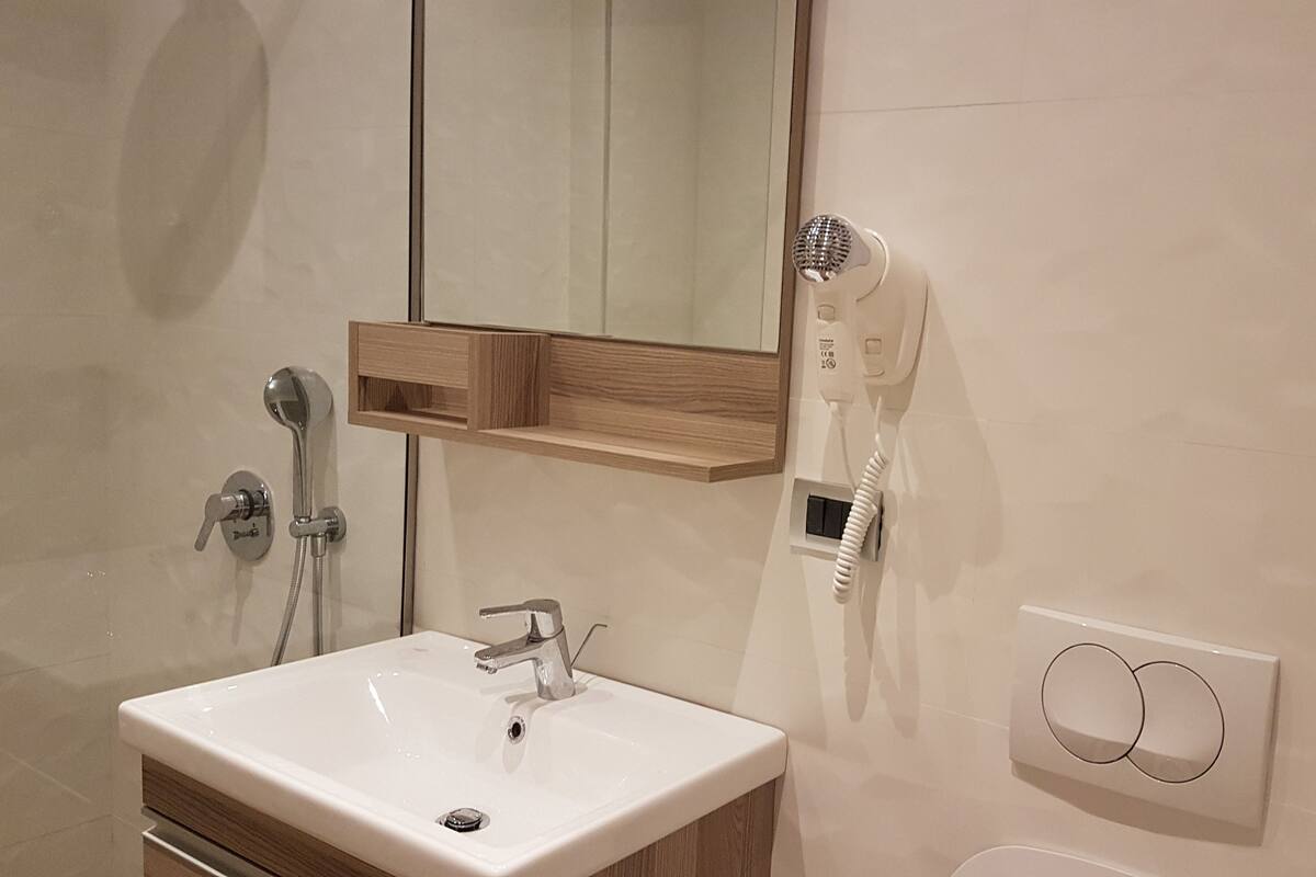 A bathroom with a sink, mirror, hairdryer, and towel rack.