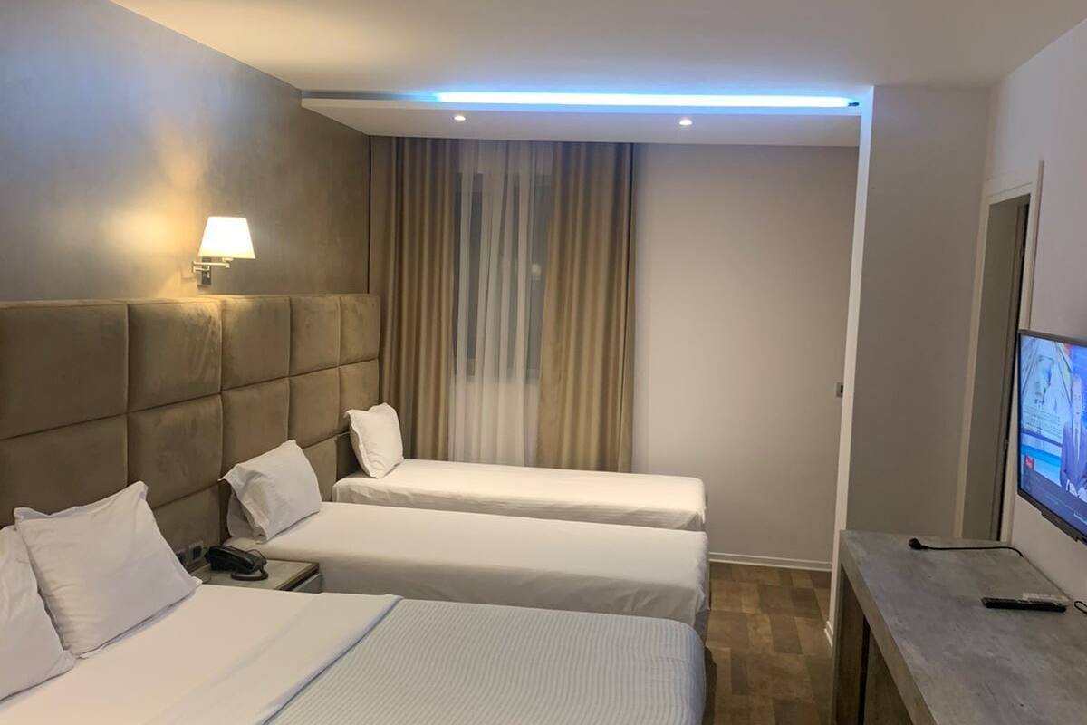 A hotel room with two beds, a desk, a television, and a lamp.