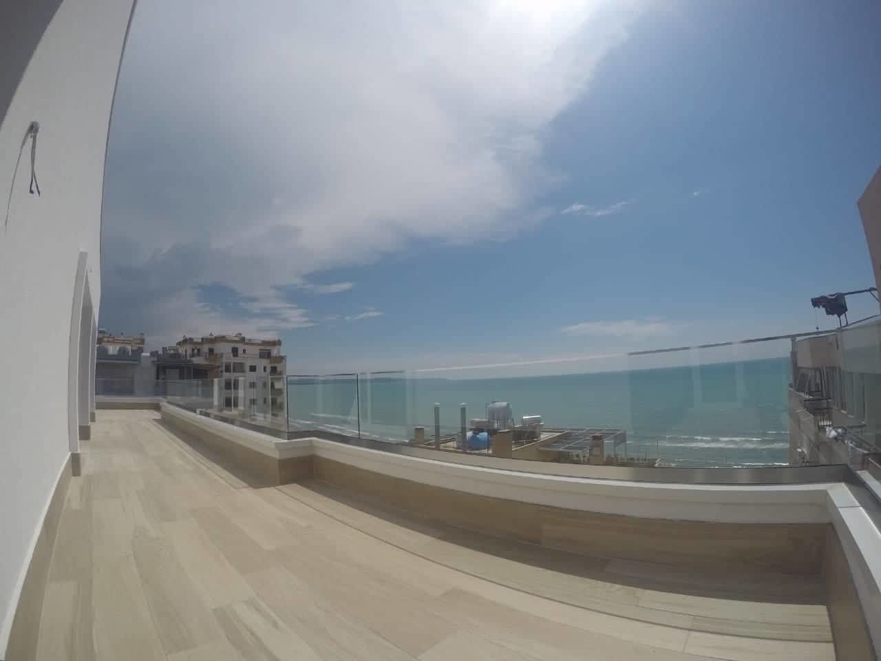 Een balkon met uitzicht op zee en gebouwen in de verte.