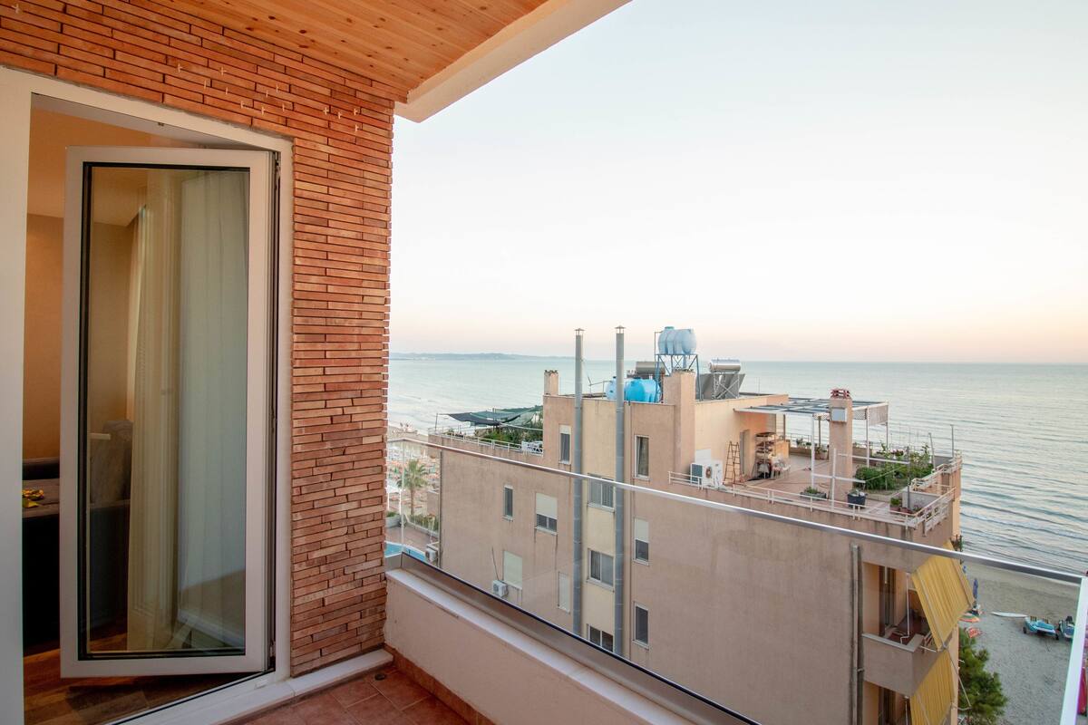A balcony with a view of the sea and buildings.