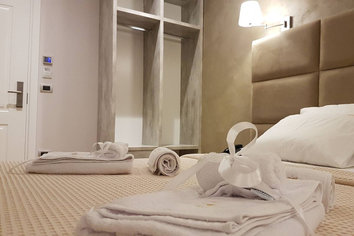 A hotel room with a bed, towels, a wardrobe, and a mirror.