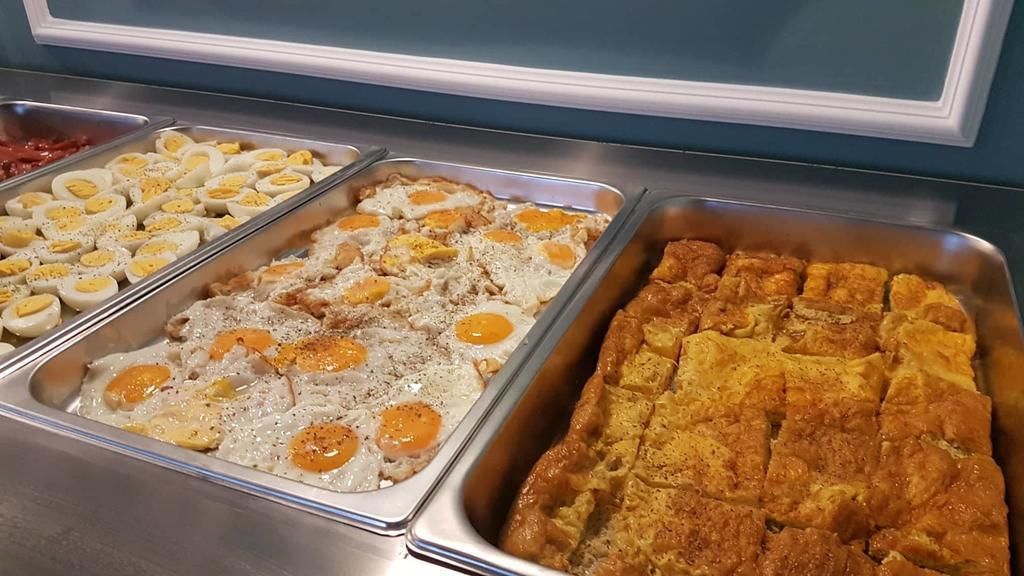 Un bufé con diversos alimentos, entre ellos huevos, carne y un plato al horno.