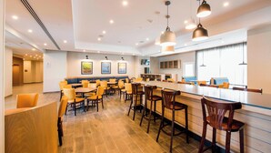 Um hall de hotel moderno com área de bar, assentos e obras de arte nas paredes.