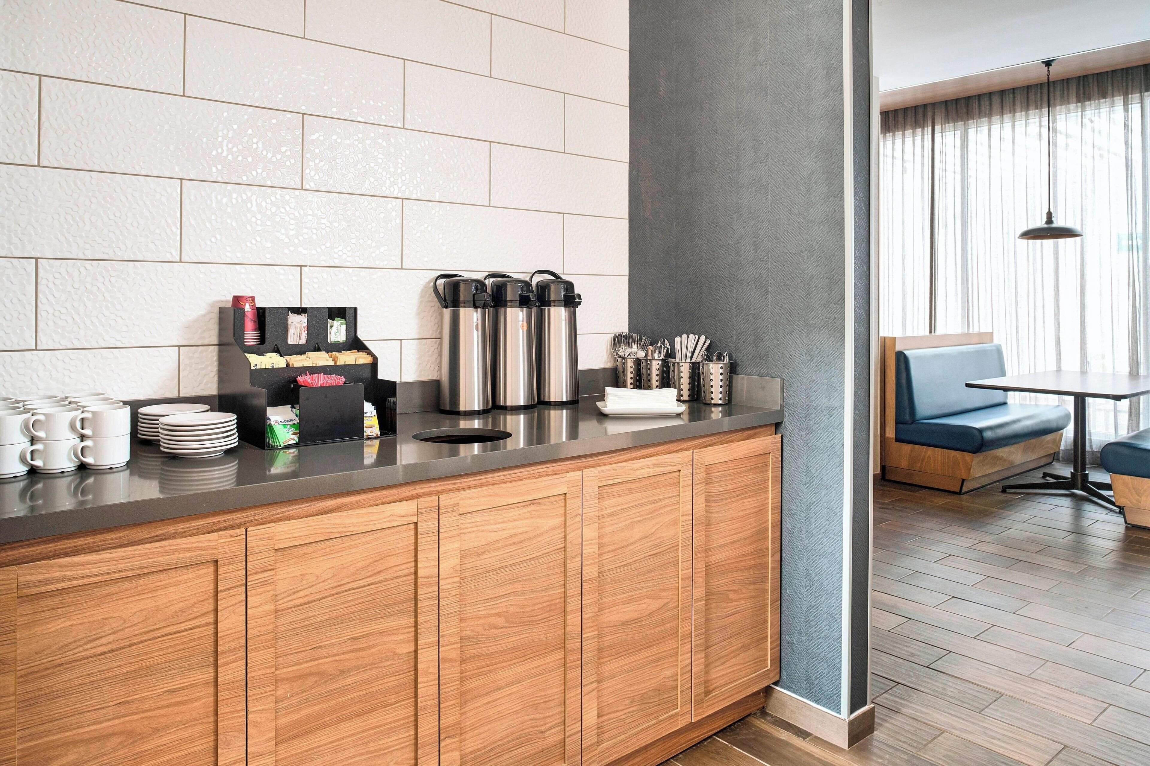 A modern kitchen with a wooden countertop, stainless steel appliances, and a seating area with a blue couch and table.