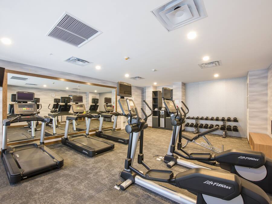 A gym with treadmills, elliptical machines, and weight benches.