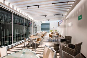 An indoor dining area with tables and chairs, a glass partition, and a ceiling with exposed beams. - Fairfield Inn & Suites by Marriott Tijuana (Tijuana)
