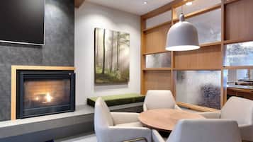 A modern living room with a fireplace, comfortable seating, and a large window with a view.
