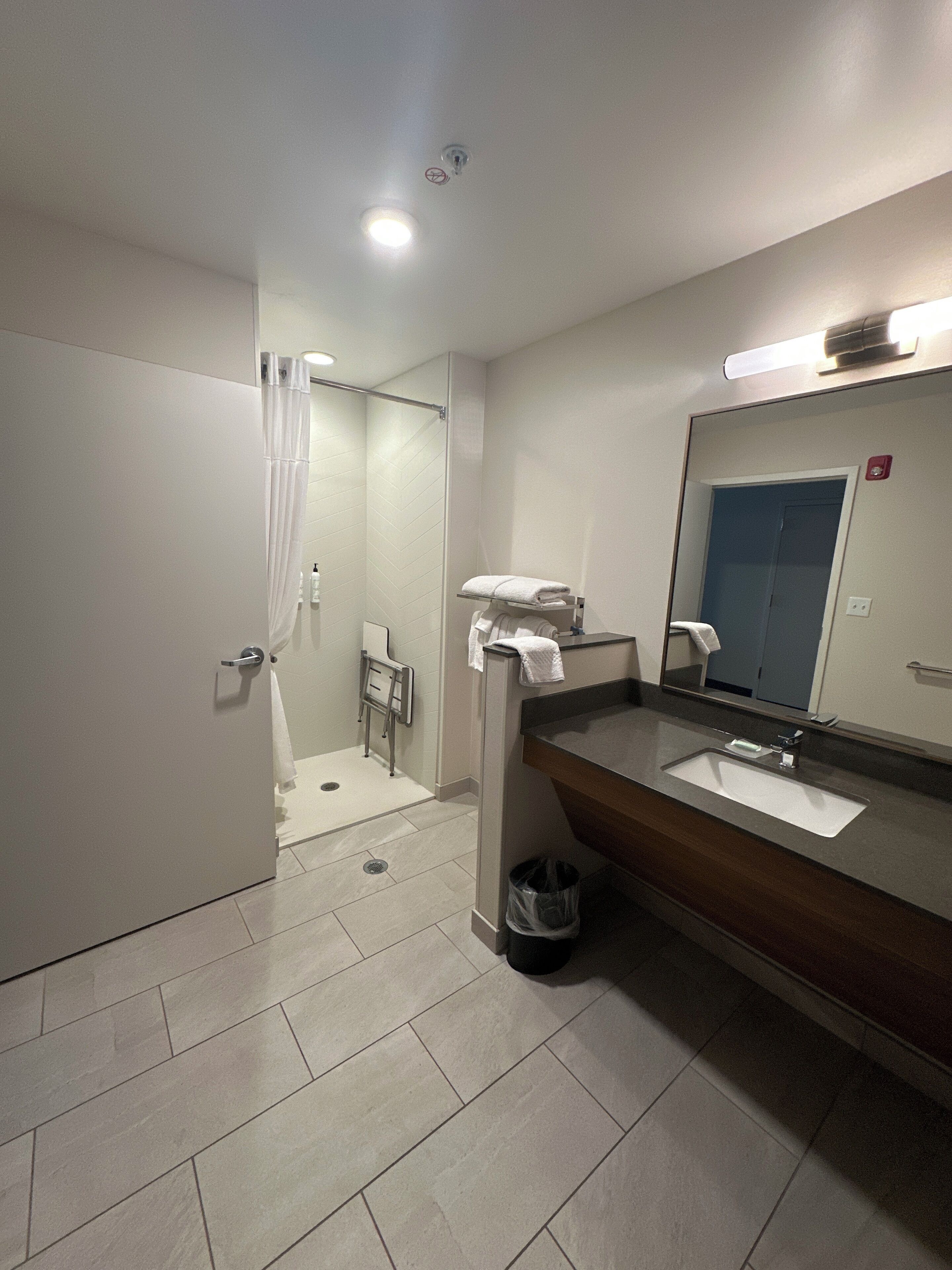 Un baño moderno con ducha, lavabo, espejo y toallero.