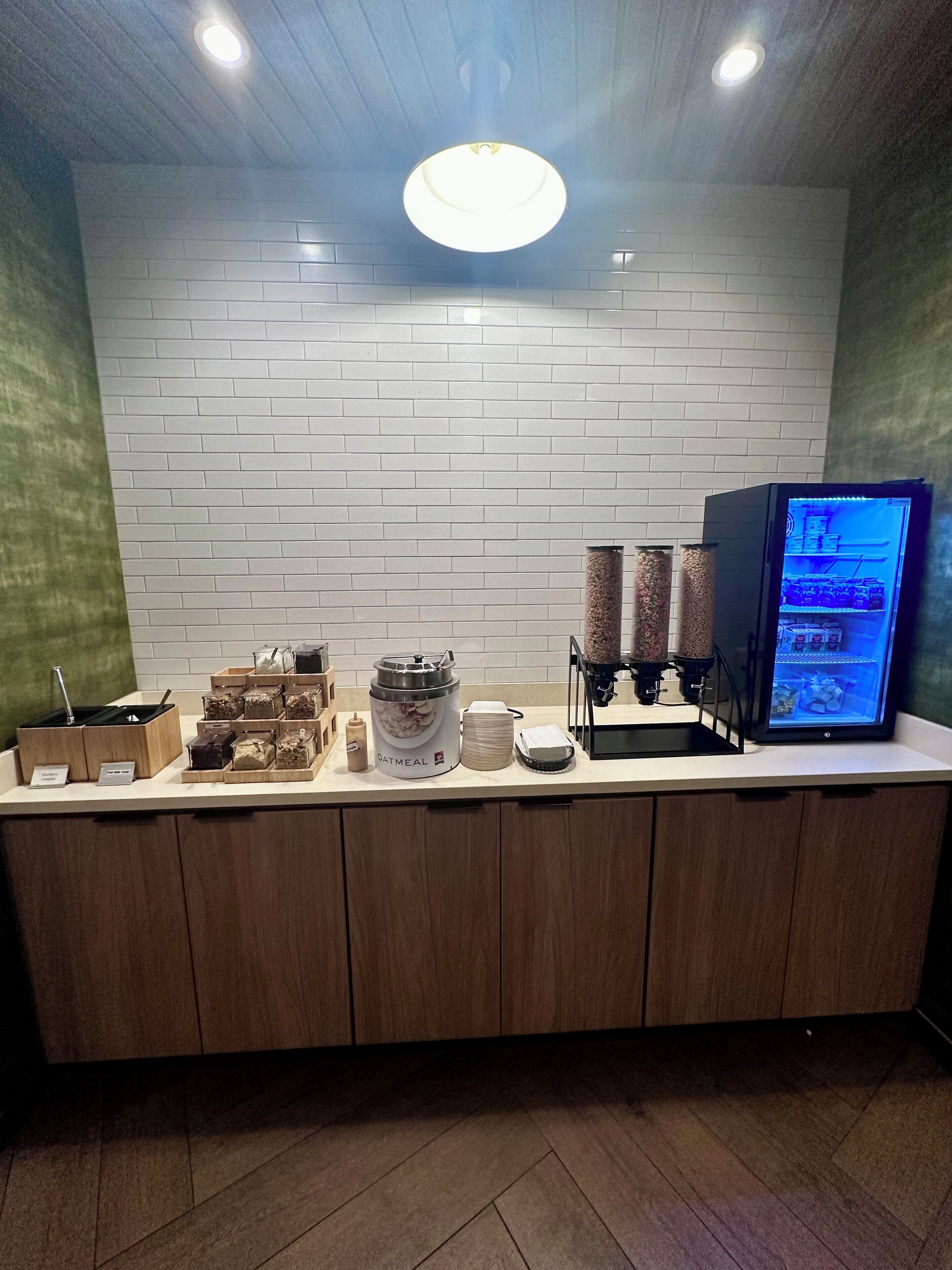 A breakfast bar with a refrigerator, coffee machine, and various food containers.