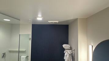 Un baño moderno con cabina de ducha de vidrio, una pared de acento oscura y un tocador con espejo.