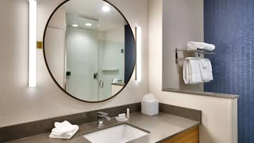 Une salle de bain moderne avec un grand miroir, un lavabo et un porte-serviettes.