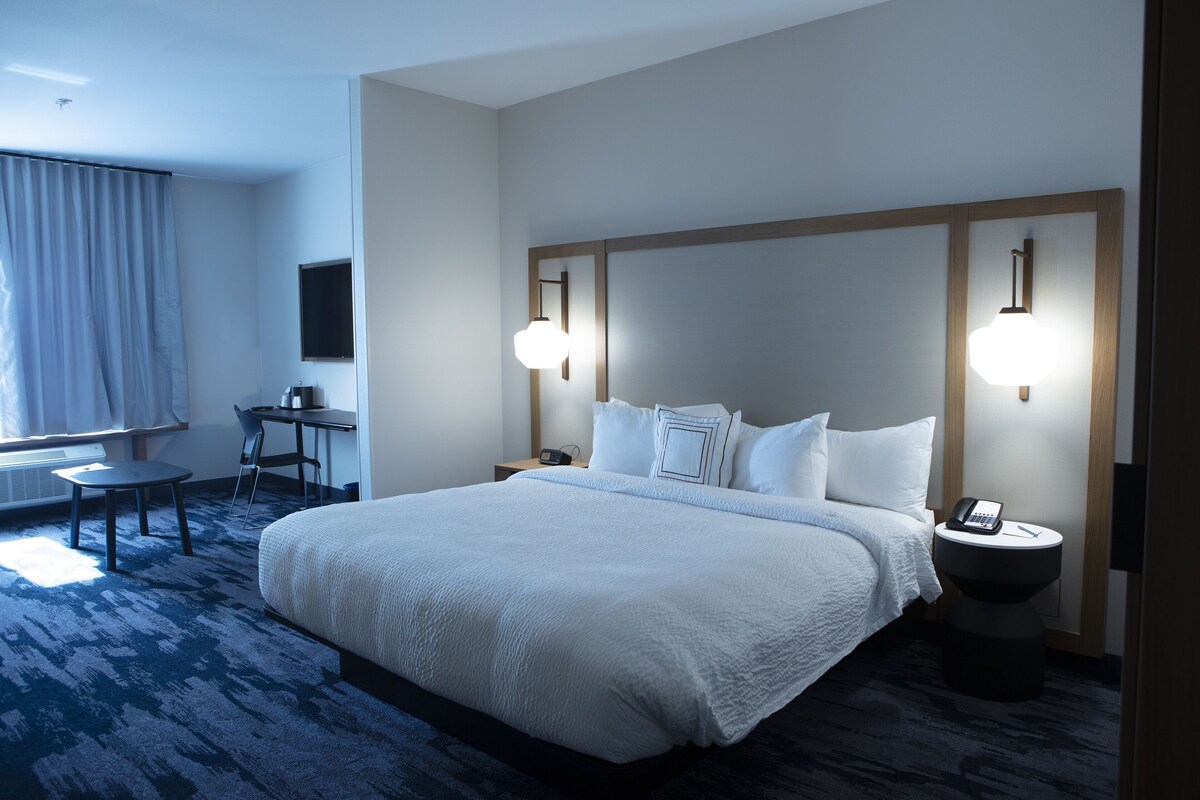 Habitación de hotel con una cama grande, un escritorio, una silla y una mesita de noche con un teléfono.