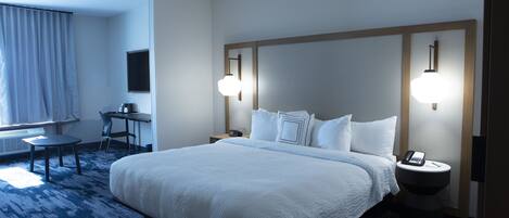 Habitación de hotel con una cama grande, un escritorio, una silla y una mesita de noche con un teléfono.