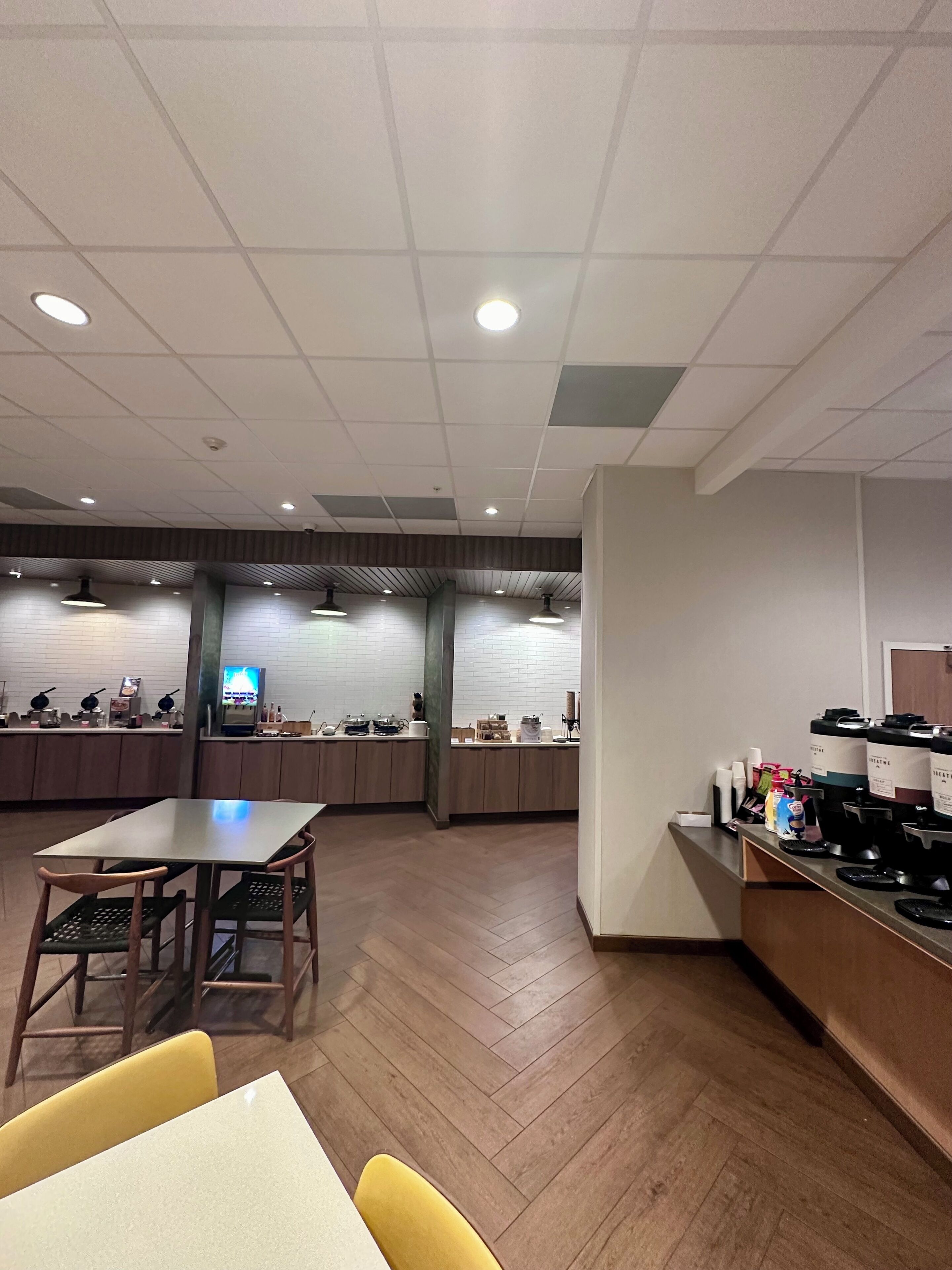En rummelig restaurant med en lang disk, flere siddeområder og et moderne loftsdesign.