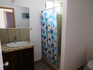 A bathroom with a tiled sink, a mirror, and a shower curtain with a marine-themed pattern. - Super Costa Rica (Bolivar)