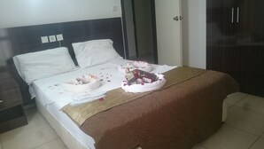 Un lit bien fait, avec une couverture marron, des oreillers blancs et un coussin décoratif orné d’un motif floral.