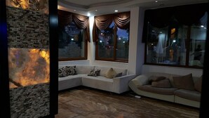Un salon moderne avec un canapé d’angle, un canapé rond et de grandes fenêtres avec des rideaux.