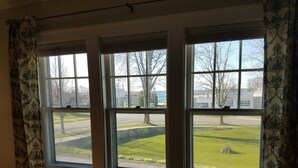 Una habitación con tres ventanas, cada una con vistas a un área verde y una carretera.