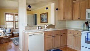 Una cocina con armarios de madera, lavavajillas blanco y microondas.