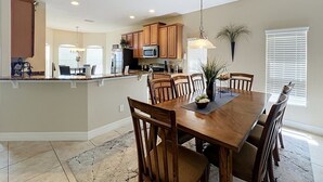 A spacious kitchen with wooden cabinets, a central island, and a dining area with a large wooden table and chairs.