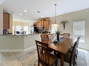A spacious kitchen with wooden cabinets, a central island, and a dining area with a large wooden table and chairs. - TRINE Retreat: Private Pool/Spa, 24/7 Support! (Davenport)
