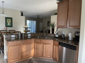A kitchen with granite countertops, wooden cabinets, a dishwasher, and a sink.