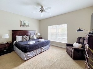 A bedroom with a bed, a nightstand, a dresser, a chair, a ceiling fan, and a window with blinds. - TRINE Retreat: Private Pool/Spa, 24/7 Support! (Davenport)