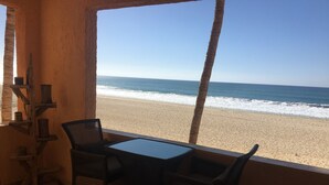 Blick auf den Strand vom Balkon mit Korbmöbeln und einem Tisch.