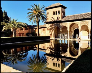 A courtyard with a pool reflecting palm trees and a building with arches and a tower. - Sun-kissed Exclusive Villa Retreat with Private Pool, Panoramic Sea Views & AC (Frigiliana)