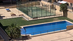 Zona de piscina en la azotea con cancha de tenis y piscina rectangular.