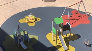 Un parque infantil con diversas estructuras de juego, incluyendo columpios, un tobogán y juegos de escalada.