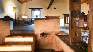 Ein rustikales Interieur mit Kamin aus Stein, Holzbalken und traditioneller Einrichtung.