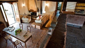 Ein Essbereich mit Holztisch und -stühlen, einem Kamin und einer Treppe, die zu einer oberen Ebene führt.