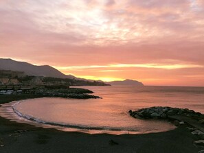 Overlooking the calm sea and surrounding mountains, this serene coastal scene offers breathtaking views.