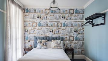 A bedroom with a large bed, a headboard, a nightstand, a lamp, a hanging light fixture, and a wall-mounted shelf.