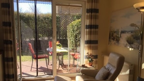 Ein Wohnzimmer mit einer Schiebeglastür, die auf eine Terrasse führt.