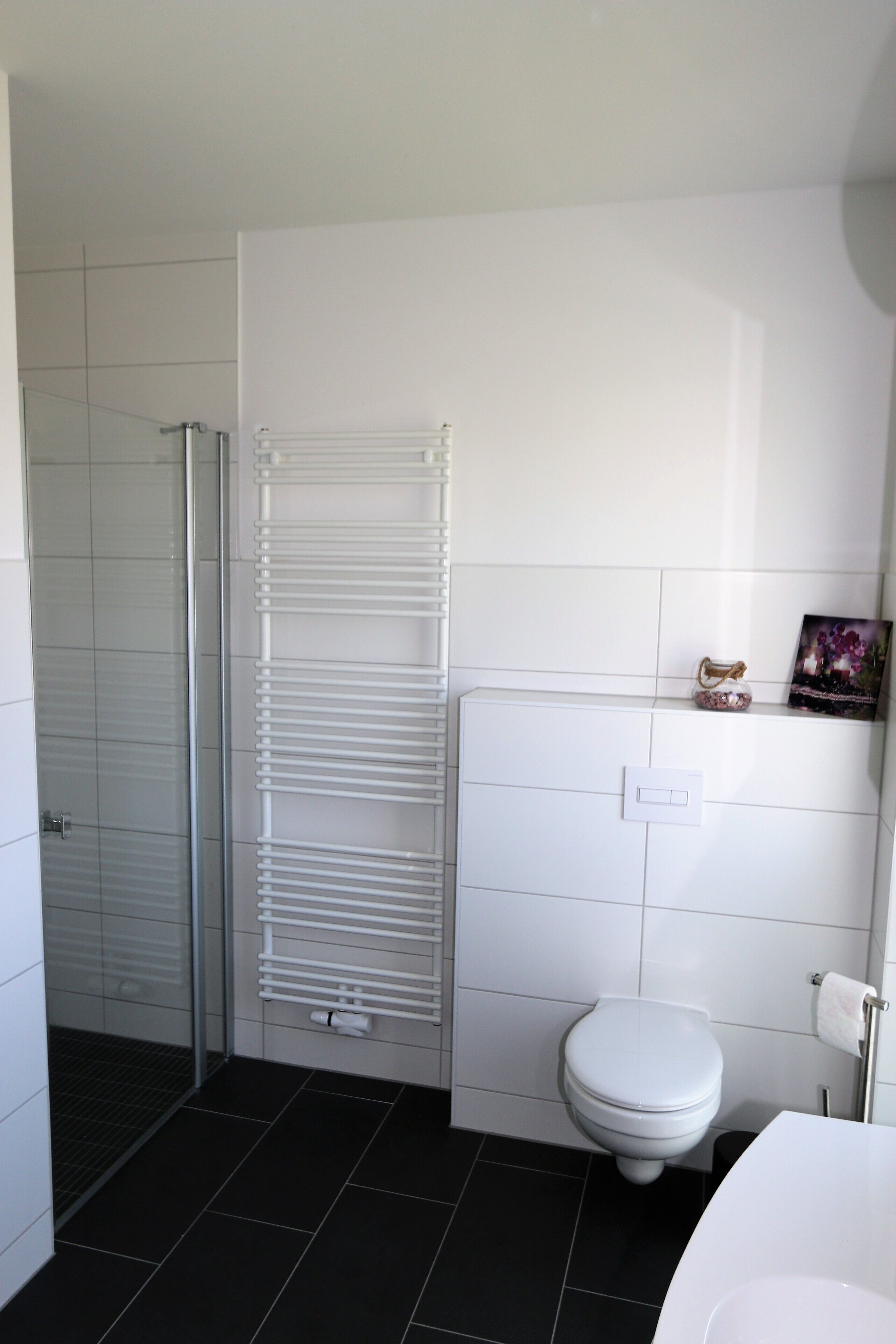 Een badkamer met douche, toilet en handdoekrek.